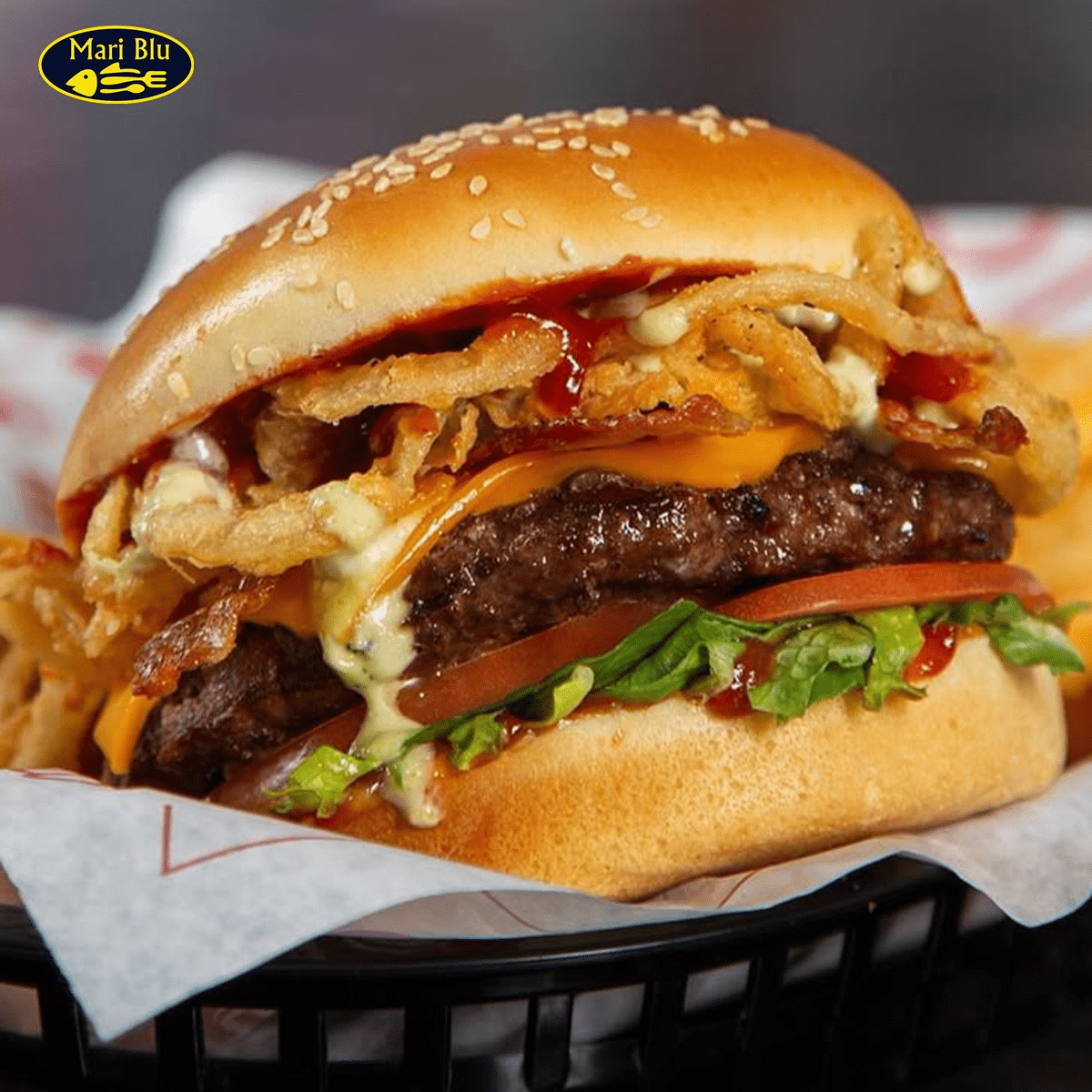 Mari Blu's Juicy Beef Burger with melted cheese, bacon, lettuce, and crispy fried onions.